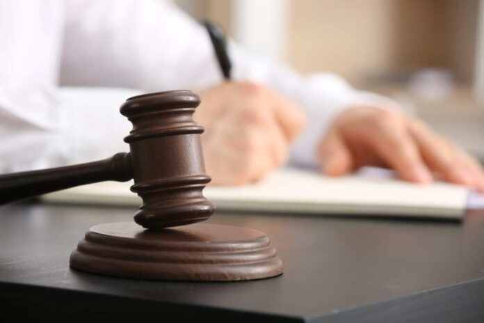 Male,Lawyer,Signing,Documents,And,Judge,Gavel,At,Table,In