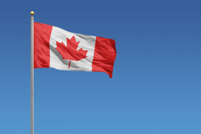 Canada,Flag,In,Front,Of,A,Clear,Blue,Sky