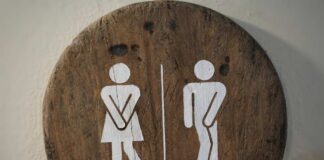Wooden restroom sign indicating mens and womens facilities with directional arrow