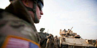 Soldiers in military gear coordinating near armored vehicles during training