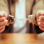 Close-up of hands holding handcuffs in a serious context