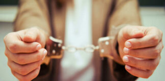 Close-up of hands holding handcuffs in a serious context