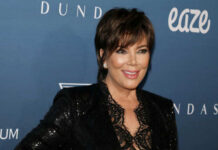 A woman in a stylish black outfit smiling at a red carpet event