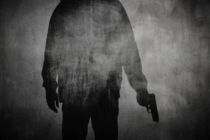 Silhouette of a person holding a gun against a textured background