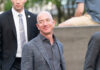 Massive AI Fund: Can Bezos Reshape Manufacturing? A man in a suit smiling while surrounded by security personnel