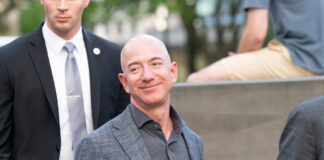 A man in a suit smiling while surrounded by security personnel