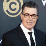 Man in a black suit smiling at a red carpet event