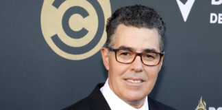 Man in a black suit smiling at a red carpet event