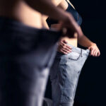 Person trying on oversized pants in front of a mirror