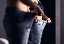 Person trying on oversized pants in front of a mirror