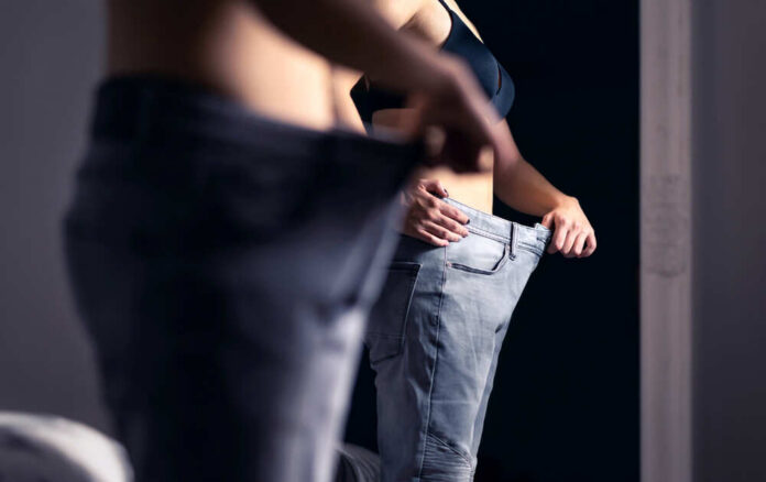 Person trying on oversized pants in front of a mirror