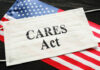 A face mask with 'CARES Act' printed on it, placed on an American flag