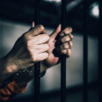 Plot to Murder U.S. Journalist Foiled Hands gripping prison bars in a dimly lit environment