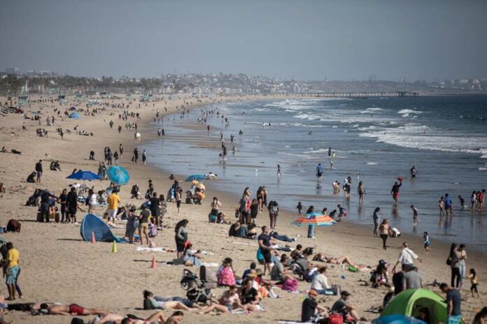 A busy beach with people sunbathing and playing in the water