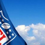 NFL flag waving against a blue sky with clouds