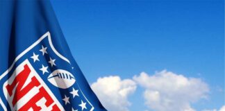 NFL flag waving against a blue sky with clouds