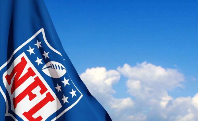 NFL flag waving against a blue sky with clouds