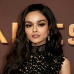 A woman with long dark hair wearing a black lace dress poses on the red carpet