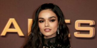 A woman with long dark hair wearing a black lace dress poses on the red carpet