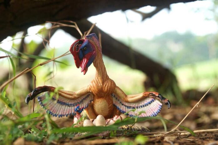 A colorful dinosaur model with wings and eggs in a natural setting