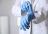 A medical professional putting on blue gloves in a clinical setting