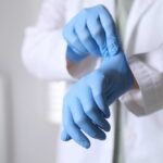 A medical professional putting on blue gloves in a clinical setting