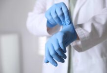 A medical professional putting on blue gloves in a clinical setting