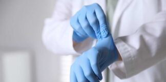 A medical professional putting on blue gloves in a clinical setting