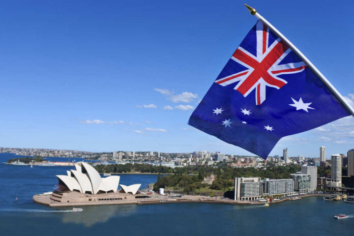Australian flag waving in front of the Sydney Opera House and city skyline