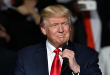 Donald Trump speaking at a rally with a microphone