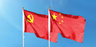 Two flags, one with the Communist Party symbol and the other with the Chinese national emblem, waving against a blue sky