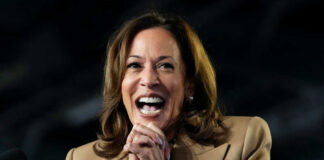 A woman in formal attire smiling broadly while speaking at a podium