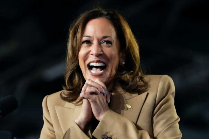 A woman in formal attire smiling broadly while speaking at a podium
