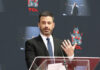 A man in a suit speaking at a podium during an event at TCL Chinese Theatre