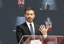 A man in a suit speaking at a podium during an event at TCL Chinese Theatre