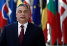 A political leader standing in front of various national flags