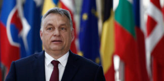 A political leader standing in front of various national flags