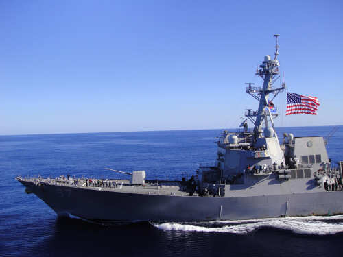 A naval destroyer sailing in the ocean with an American flag