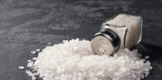 A glass salt shaker tipped over with salt spilling out