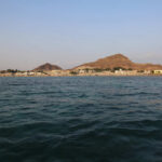 A coastal view featuring a village by the sea and mountains in the background