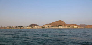 A coastal view featuring a village by the sea and mountains in the background