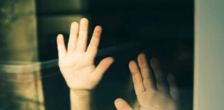 Child's hands pressed against a window, creating a reflective image