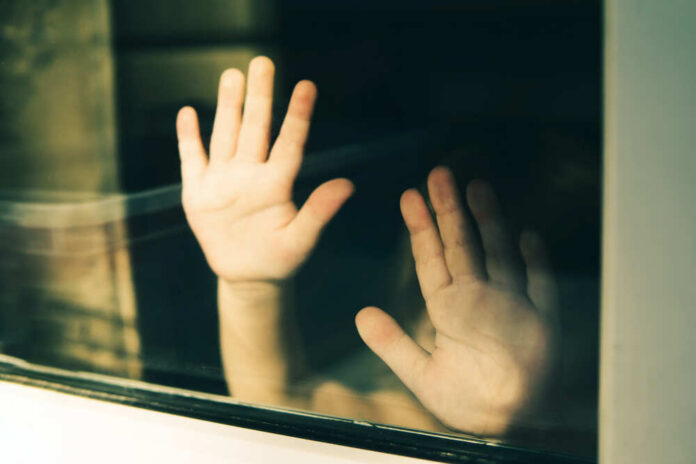 Child's hands pressed against a window, creating a reflective image