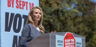 Speaker at a podium addressing a crowd at a political rally