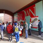 Students gathered outside a building at Brown University, engaging with informational materials