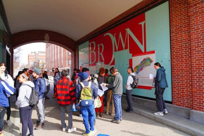 Students gathered outside a building at Brown University, engaging with informational materials