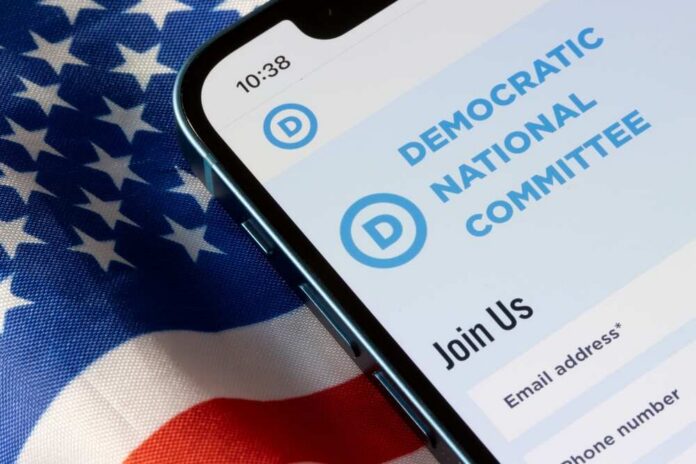 shutterstock_2223653467.jpg Mobile phone displaying Democratic National Committee website on an American flag background