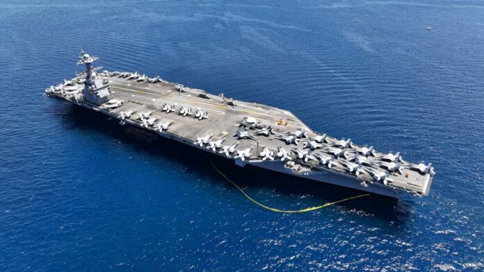 An aircraft carrier with numerous fighter jets on its deck in the ocean
