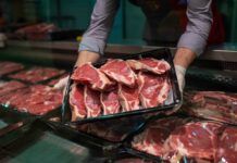 A butcher holding a tray of fresh meat cuts