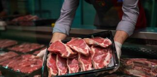 A butcher holding a tray of fresh meat cuts